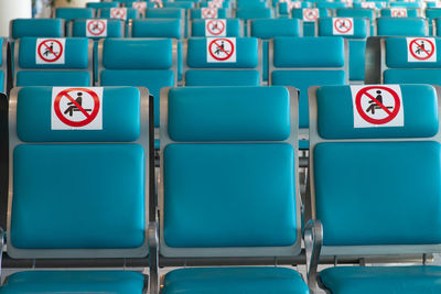 Airport during coronavirus pandemic. social distancing. empty blue chairs restricted no-sitting sign