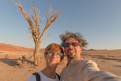 Portrait of smiling couple at sossusvlei against clear sky