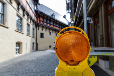 Close-up of yellow umbrella on street against buildings