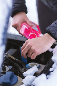 Cropped image of man pouring petrol in car engine during winter