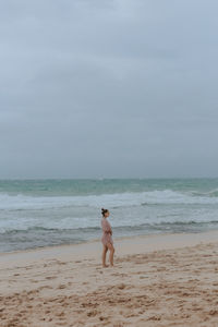 Full length of shirtless man on beach against sky