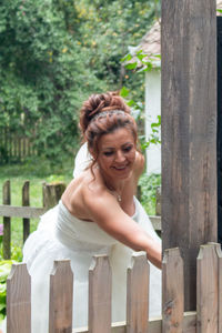 Smiling bride standing by fence