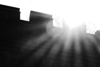 Low angle view of sun shining through built structure