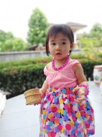 Cute girl in pink dress standing at park