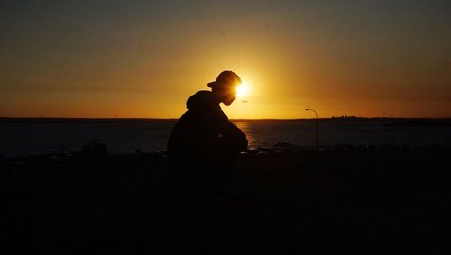 Silhouette man on beach against sky during sunset