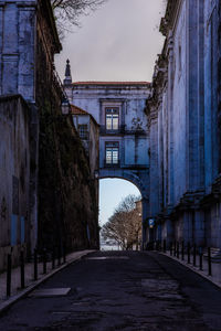 Empty road amidst buildings against sky in city