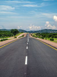 Road leading towards mountain against sky