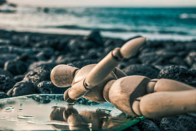 Low section of person relaxing on rock at beach