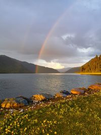 Scenic view of rainbow over lake against sky