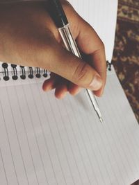 Cropped hand of person writing in book