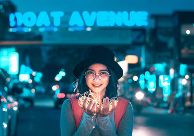 Portrait of a smiling young woman in city at night