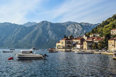 Sailboats in sea by buildings against sky