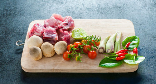 Tomatoes and meat on cutting board over table