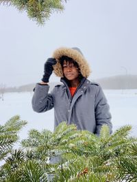 Portrait of woman standing by tree during winter

