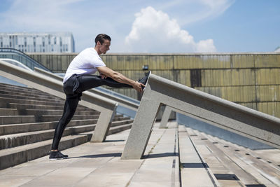 Side view of man on railing against sky