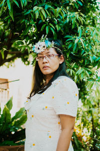 Portrait of a beautiful young woman standing against plants