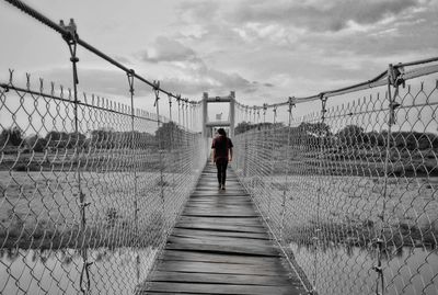 Rear view of man walking on footbridge