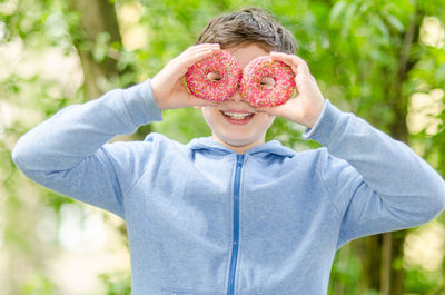 Portrait of smiling boy looking through donuts