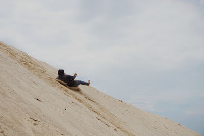 Man sitting on beach against sky