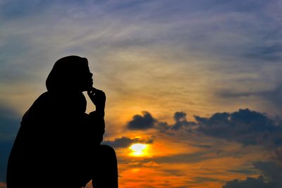 Silhouette man photographing against sky during sunset