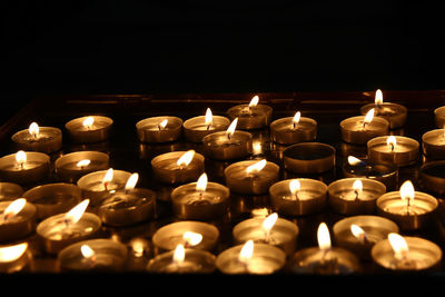 Close-up of illuminated tea light candles in darkroom