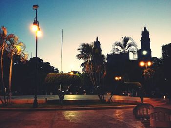 Illuminated street light against sky at sunset