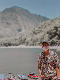 Portrait of woman wearing sunglasses standing on mountain against sky