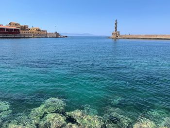 Scenic view of sea against buildings against clear blue sky