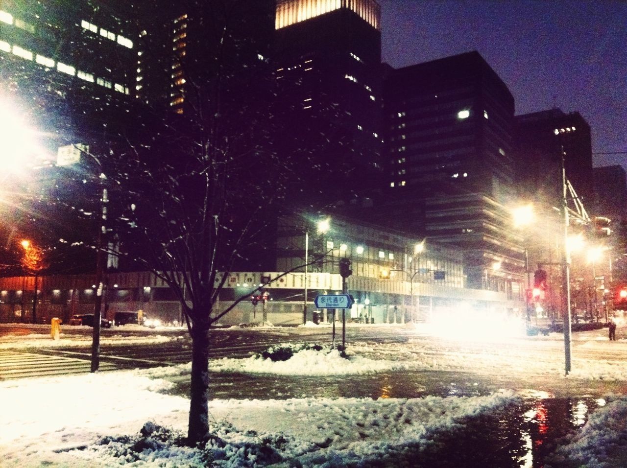 illuminated, night, building exterior, street light, street, architecture, built structure, city, transportation, lighting equipment, snow, winter, season, car, land vehicle, city street, road, city life, building, cold temperature