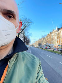 Portrait of man on road against sky in city