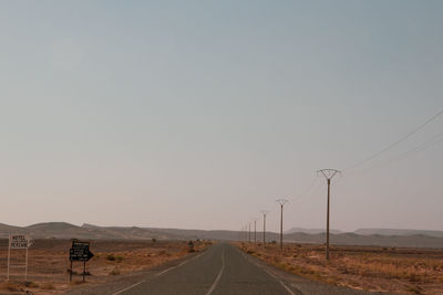 Road leading towards desert against clear sky. través car