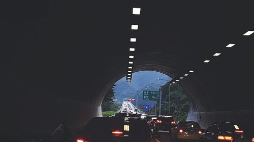 Cars on illuminated road in city against sky at night