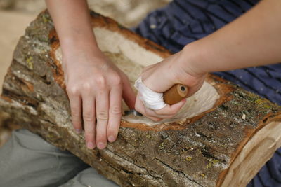 Midsection of man carving log