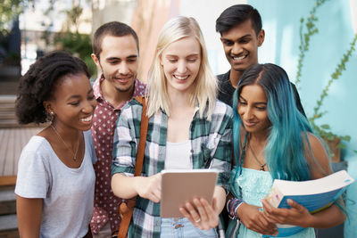 Cheerful friends using digital tablet