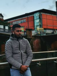 Young man standing by railing in city