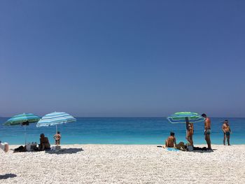 People on beach against clear sky