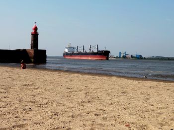 Lighthouse on beach against clear sky