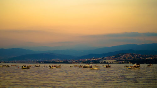 Boats in sea at sunset