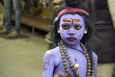 Close-up of woman with statue against black background