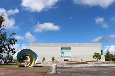 Road by building against blue sky