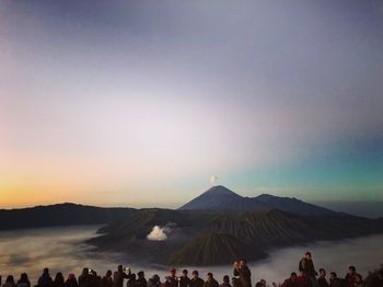 People on mountain against sky during sunset