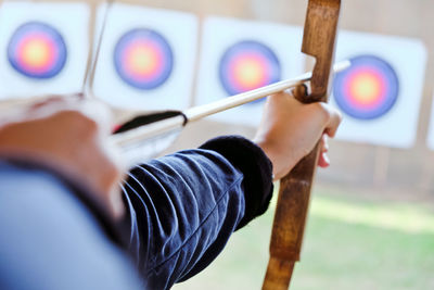 Cropped hands of woman with bow and arrow aiming at target