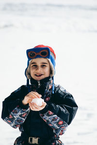Portrait of smiling young woman standing on snow