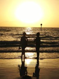 Silhouette of people on beach at sunset