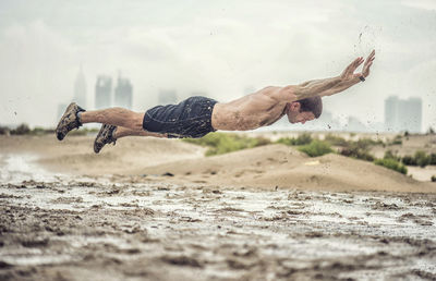 Close-up of athletic man exercising in mud during rainy season