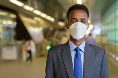 Portrait of young man wearing mask standing at airport