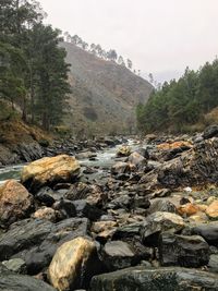 Rocks by river against sky