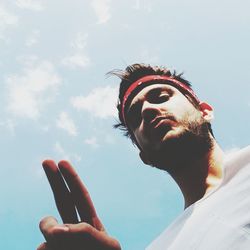 Low angle view of hand holding smart phone against sky