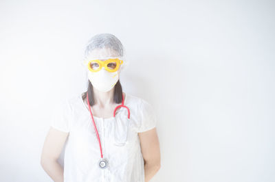 Portrait of teenage girl wearing sunglasses standing against white background