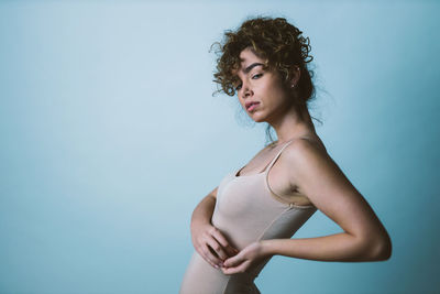 Portrait of woman standing against blue background